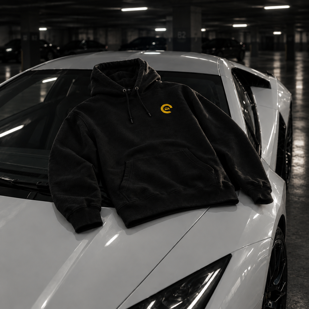 Hoodie Carspot noir brodé posé sur le capot d'une supercar blanche
