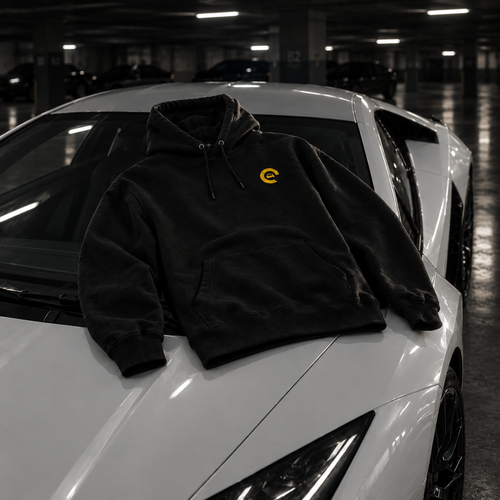 Hoodie Carspot noir brodé posé sur le capot d'une supercar blanche