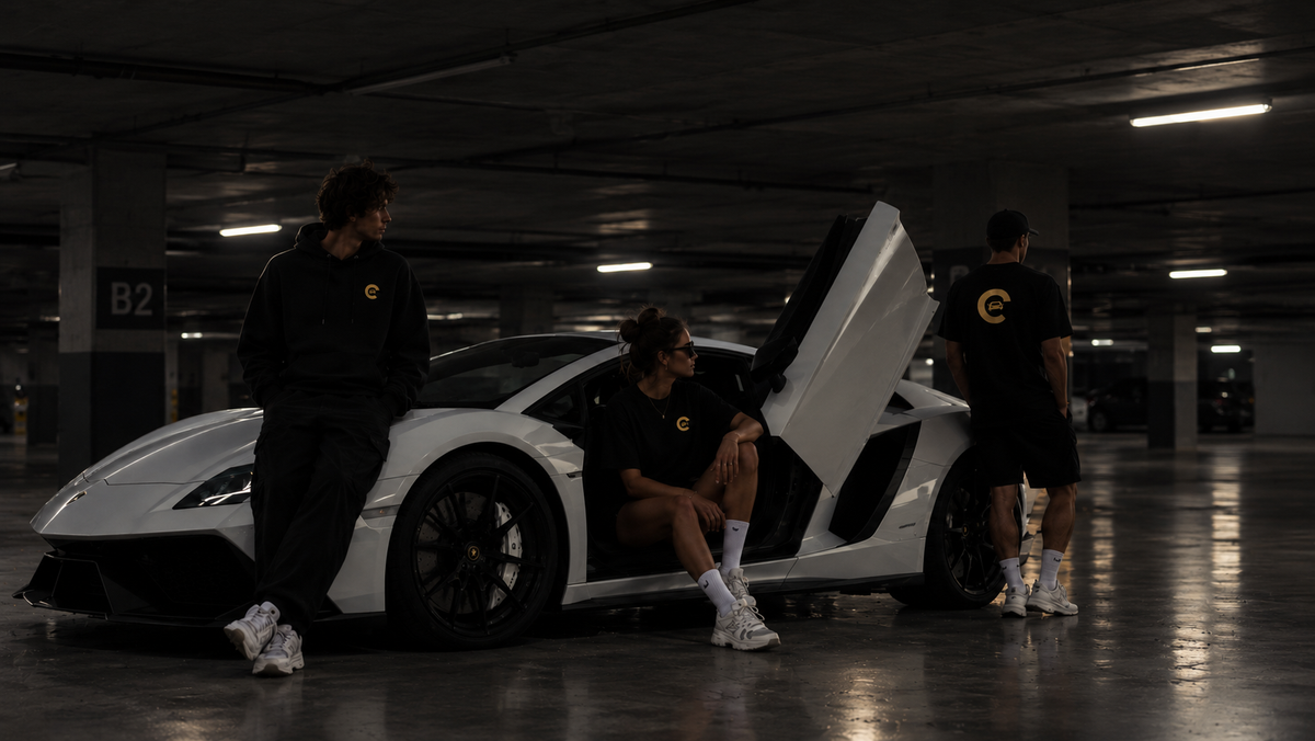 Three spotters in a Carspot hoodie, T-shirt and cap around a white supercar in a car park